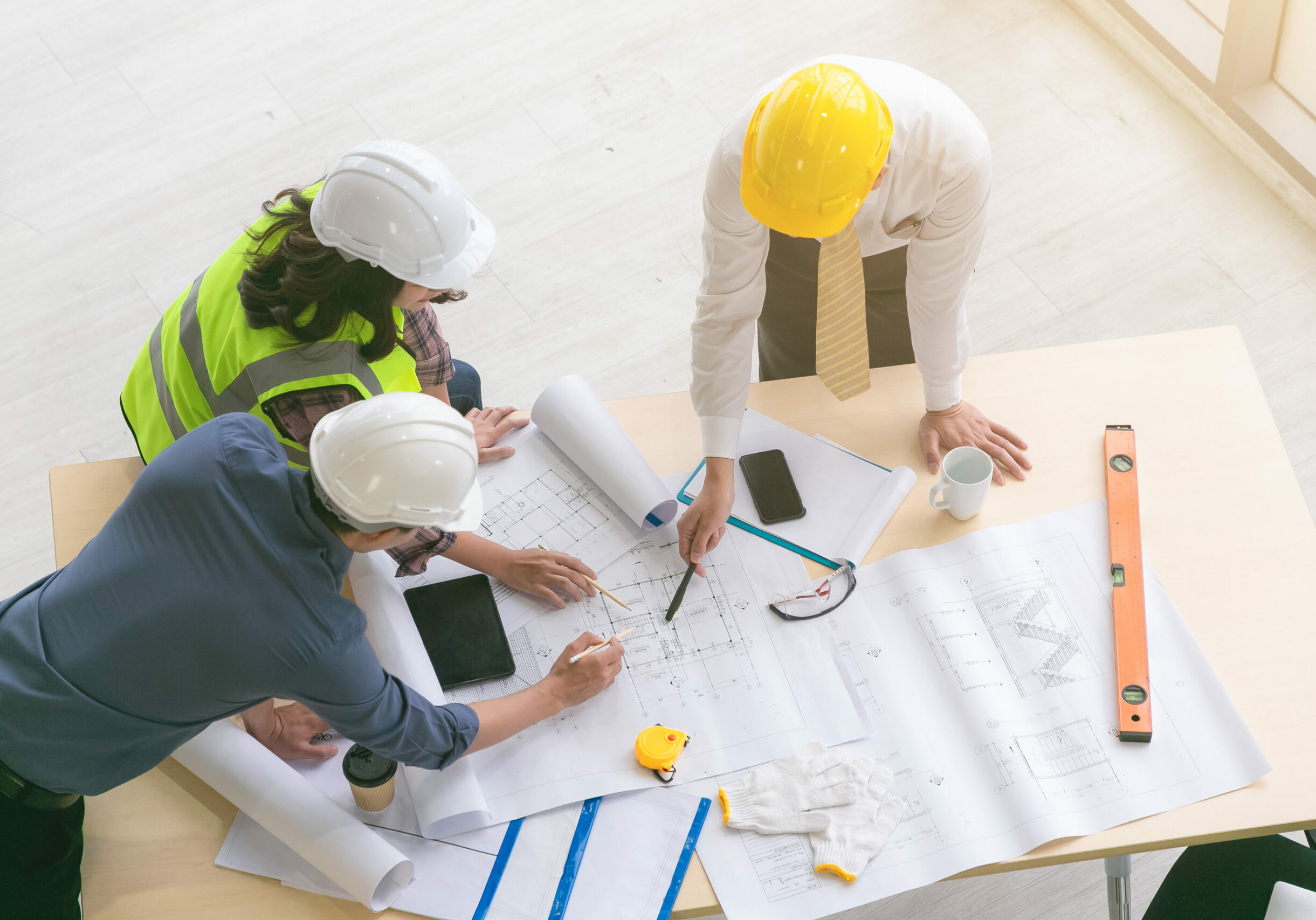 Team of engineers and architects working, planing, measuring layout of building blueprints in construction site. top view
